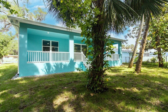 view of front of house featuring stucco siding, covered porch, and a front yard