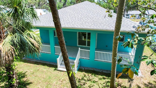 view of front of home with roof with shingles, a front yard, and covered porch