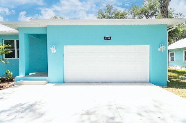 view of front of house featuring stucco siding, an attached garage, and driveway