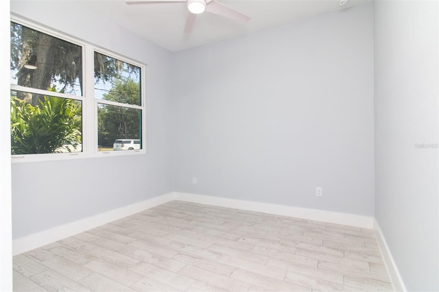 empty room featuring baseboards, a ceiling fan, and light wood-style floors