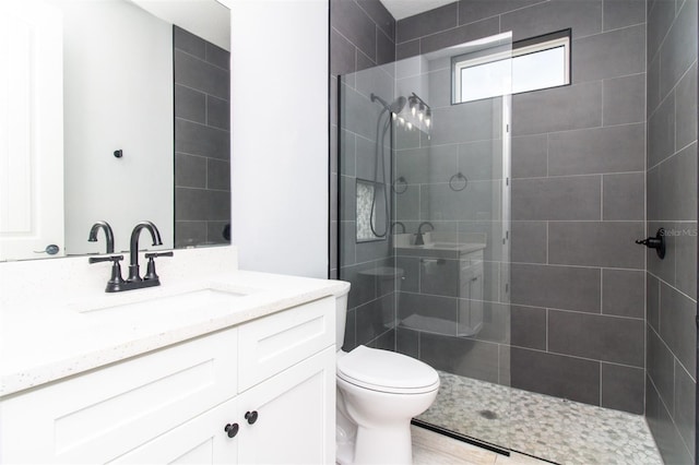 bathroom with toilet, vanity, and tiled shower