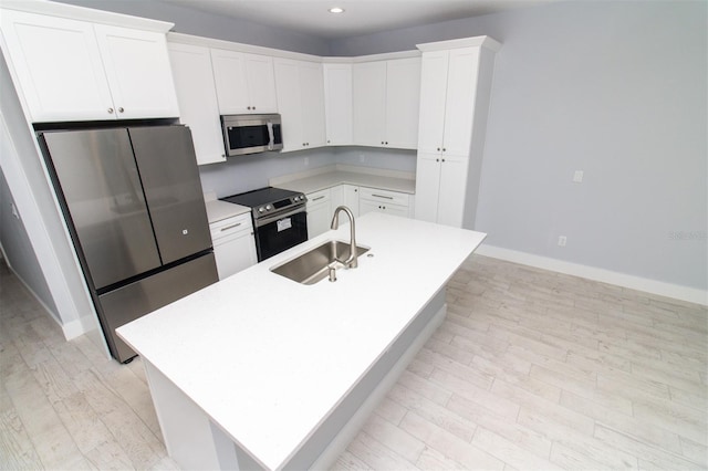 kitchen featuring stainless steel appliances, a sink, baseboards, light wood-style floors, and light countertops