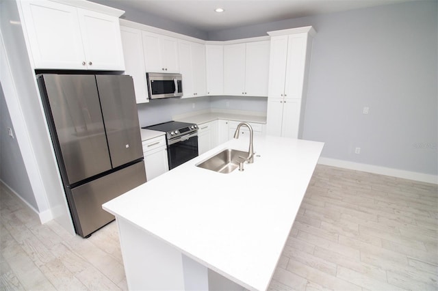 kitchen featuring a sink, light wood-style floors, stainless steel appliances, baseboards, and white cabinetry