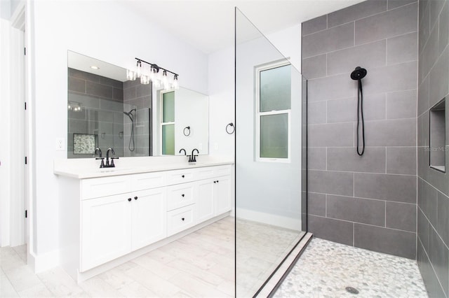 bathroom with walk in shower, baseboards, a sink, and double vanity