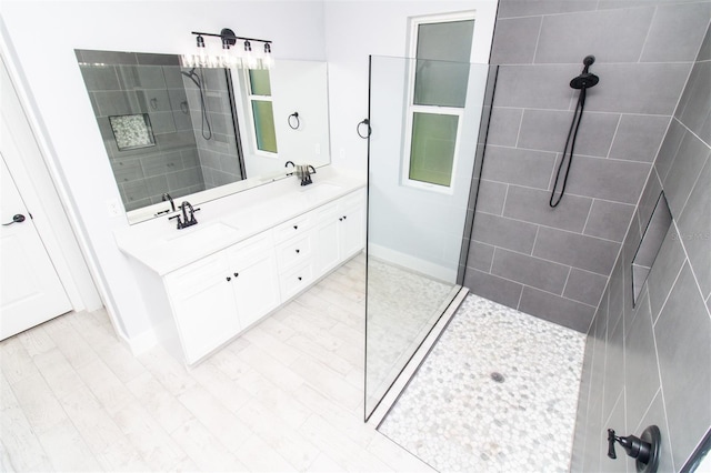 bathroom featuring double vanity, baseboards, a sink, and a walk in shower