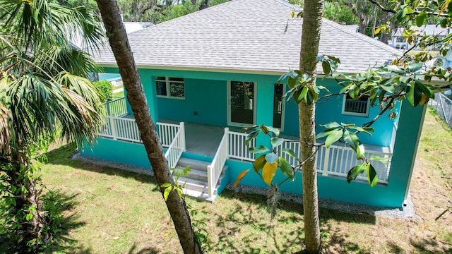 back of house with roof with shingles and a yard