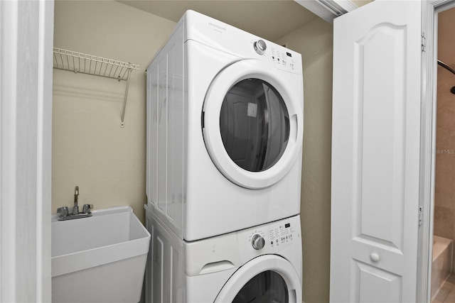 laundry room with stacked washer / drying machine, a sink, and laundry area