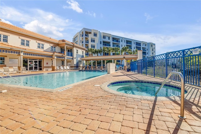 pool with fence, a community hot tub, and a patio area
