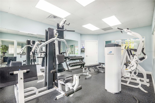 exercise room featuring a drop ceiling, visible vents, and baseboards