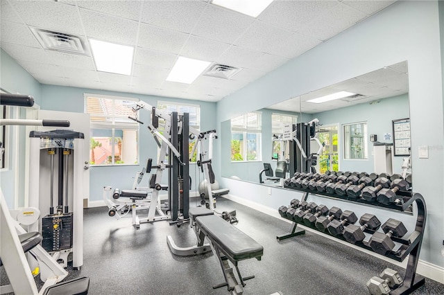 exercise room featuring a paneled ceiling, visible vents, and baseboards