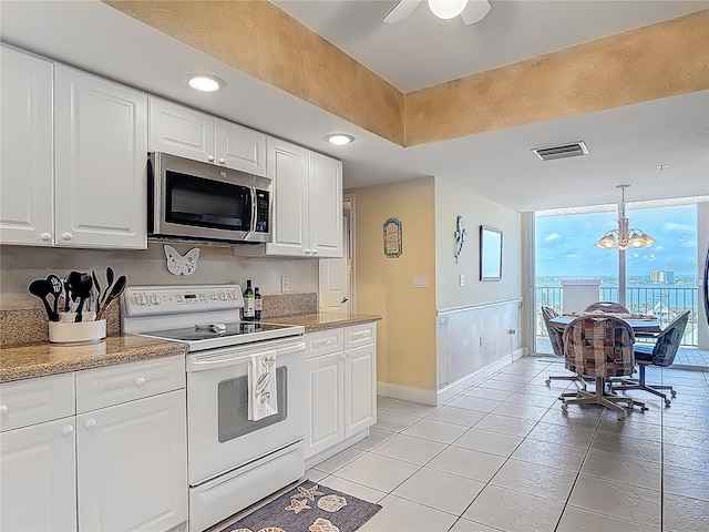 3145 S Atlantic Ave Unit 1001, Daytona Beach, FL 32118 - kitchen featuring stainless steel microwave, white electric range oven, light tile patterned floors, baseboards, and white cabinets