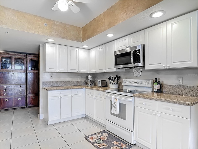 3145 S Atlantic Ave Unit 1001, Daytona Beach, FL 32118 - kitchen featuring stainless steel microwave, light tile patterned floors, white cabinetry, and white electric range oven