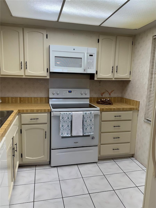 4175 S Atlantic Ave Unit 5280, New Smyrna Beach, FL 32169 - kitchen featuring white appliances, wallpapered walls, light tile patterned floors, and a sink