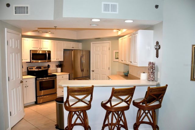 5300 S Atlantic Ave Unit 8-402, New Smyrna Beach, FL 32169 - kitchen featuring appliances with stainless steel finishes, visible vents, a peninsula, and a kitchen bar