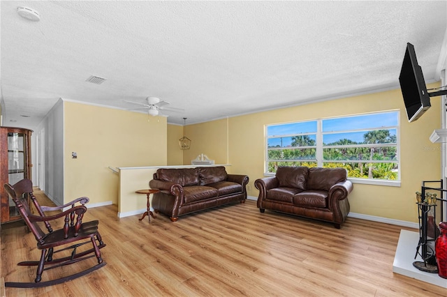 216 Dune Cir, New Smyrna Beach, FL 32169 - living room featuring a textured ceiling, light wood-style floors, visible vents, baseboards, and a ceiling fan
