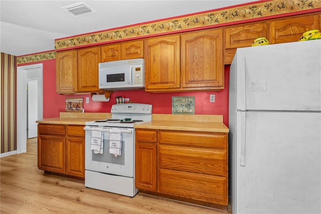 216 Dune Cir, New Smyrna Beach, FL 32169 - kitchen with visible vents, white appliances, light countertops, and light wood finished floors