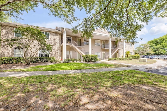 160 Reserve Cir Unit 204, Oviedo, FL 32765 - view of front of home with uncovered parking, a front lawn, stairway, and brick siding