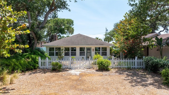 825 E 23rd Ave, New Smyrna Beach, FL 32169 - view of front of house with a fenced front yard, a shingled roof, and a chimney