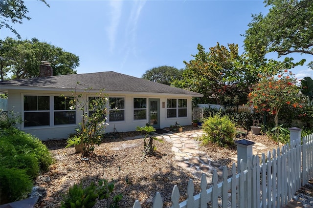 825 E 23rd Ave, New Smyrna Beach, FL 32169 - view of front of house featuring fence private yard, a shingled roof, and a chimney