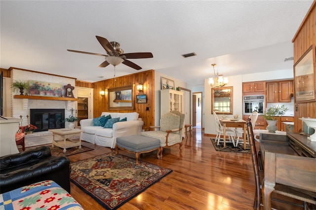 825 E 23rd Ave, New Smyrna Beach, FL 32169 - living area with visible vents, a brick fireplace, wood walls, wood finished floors, and ceiling fan with notable chandelier