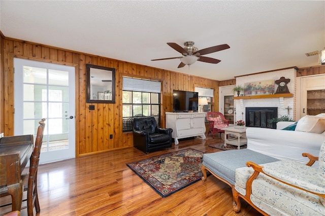 825 E 23rd Ave, New Smyrna Beach, FL 32169 - living area featuring wood finished floors, a fireplace, baseboards, wooden walls, and a ceiling fan