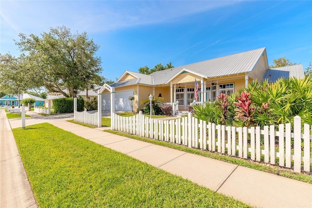 2815 Bay Side Dr, New Smyrna Beach, FL 32168 - view of front facade with metal roof, a front yard, an attached garage, a porch, and a fenced front yard