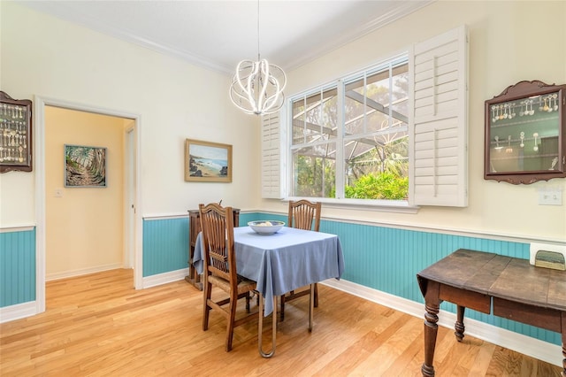 2815 Bay Side Dr, New Smyrna Beach, FL 32168 - dining space with crown molding, a wainscoted wall, baseboards, wood finished floors, and a notable chandelier