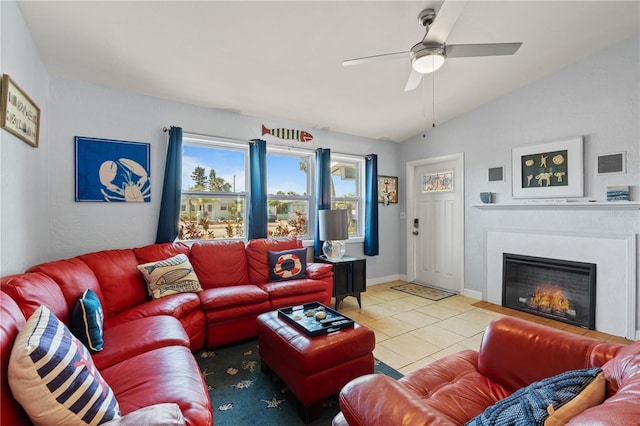 living area featuring visible vents, a glass covered fireplace, a ceiling fan, light tile patterned floors, and vaulted ceiling
