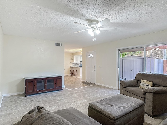 95 Moonstone Ct, Port Orange, FL 32129 - living room featuring a ceiling fan, light wood-style flooring, a textured ceiling, and baseboards