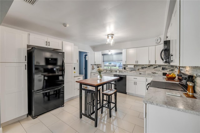 2548 E Compton St, Orlando, FL 32806 - kitchen featuring backsplash, light stone countertops, a sink, white cabinets, and black appliances