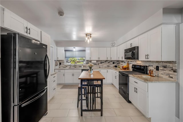 2548 E Compton St, Orlando, FL 32806 - kitchen featuring light countertops, white cabinetry, tasteful backsplash, a sink, and black appliances