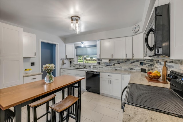 2548 E Compton St, Orlando, FL 32806 - kitchen featuring white cabinets, light stone counters, a sink, backsplash, and black appliances
