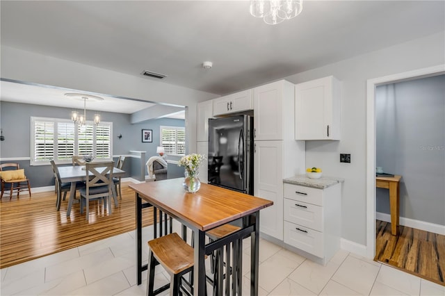 2548 E Compton St, Orlando, FL 32806 - kitchen featuring an inviting chandelier, freestanding refrigerator, visible vents, baseboards, and white cabinets