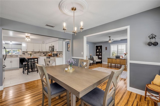 2548 E Compton St, Orlando, FL 32806 - dining room with baseboards, ceiling fan with notable chandelier, light wood-style flooring, and visible vents