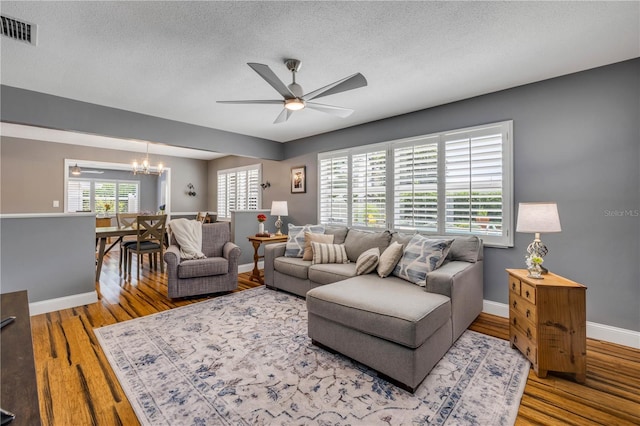 2548 E Compton St, Orlando, FL 32806 - living room featuring a textured ceiling, visible vents, wood finished floors, baseboards, and ceiling fan with notable chandelier