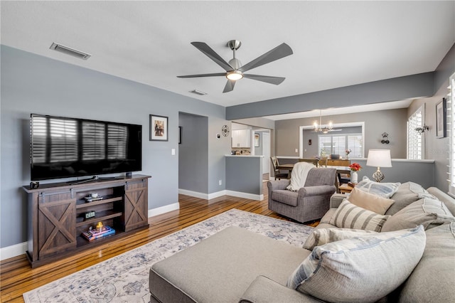 2548 E Compton St, Orlando, FL 32806 - living room featuring baseboards, ceiling fan with notable chandelier, wood finished floors, and visible vents