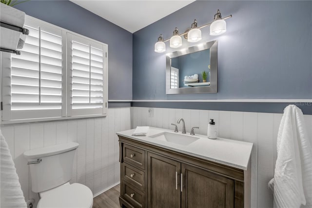 2548 E Compton St, Orlando, FL 32806 - half bathroom featuring toilet, wainscoting, wood finished floors, and vanity