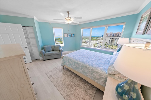 bedroom featuring a ceiling fan, crown molding, baseboards, a closet, and light wood-style floors