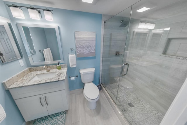 full bathroom featuring vanity, toilet, baseboards, and a stall shower