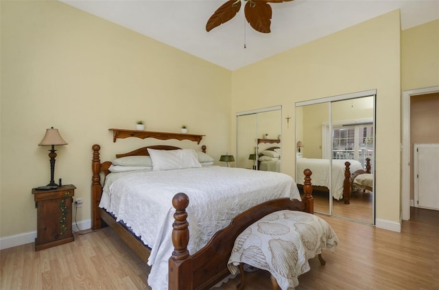 bedroom featuring light wood-style floors, baseboards, ceiling fan, and two closets