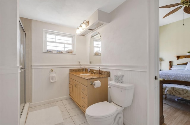 full bath with a ceiling fan, connected bathroom, a wainscoted wall, and toilet