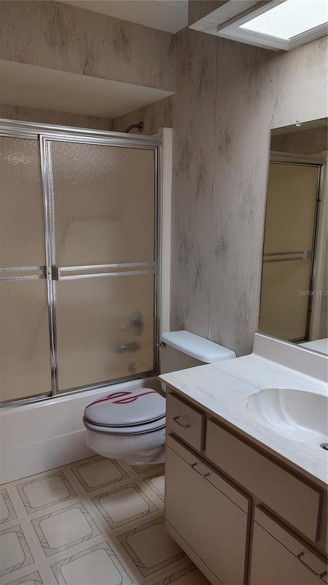 bathroom with shower / bath combination with glass door, toilet, and vanity