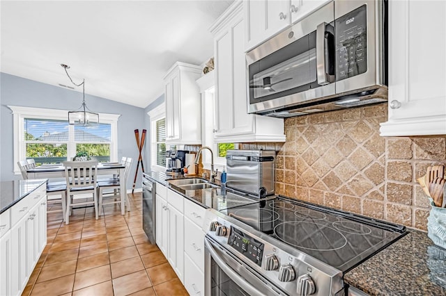 kitchen with appliances with stainless steel finishes, a sink, white cabinetry, decorative backsplash, and lofted ceiling