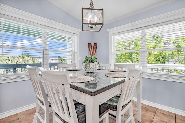 tiled dining space featuring baseboards and a notable chandelier