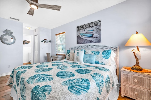 bedroom featuring visible vents, wood finished floors, baseboards, ensuite bathroom, and ceiling fan