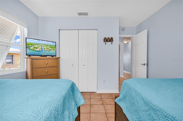 bedroom featuring light tile patterned flooring, baseboards, visible vents, and a closet