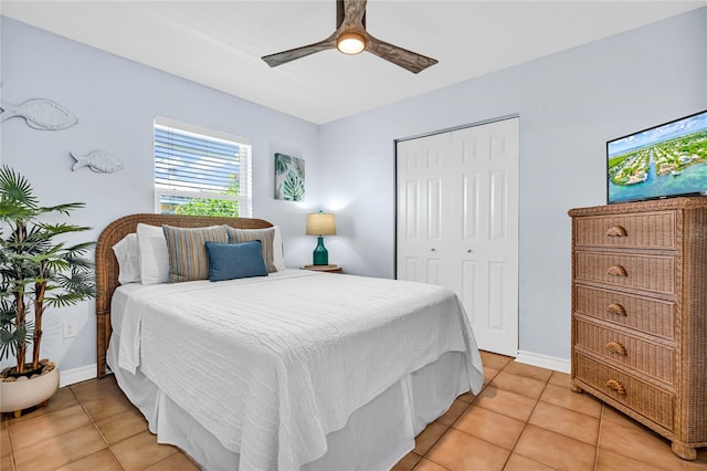 bedroom with baseboards, ceiling fan, light tile patterned floors, and a closet