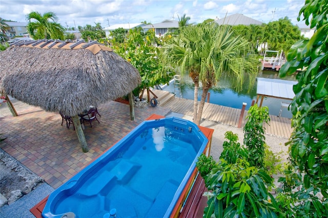 view of pool with fence, a patio, a water view, and a dock