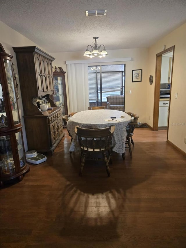 dining area with a textured ceiling, a chandelier, baseboards, visible vents, and dark wood-style floors
