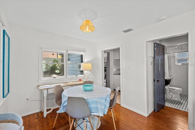 dining space featuring baseboards, wood finished floors, and visible vents